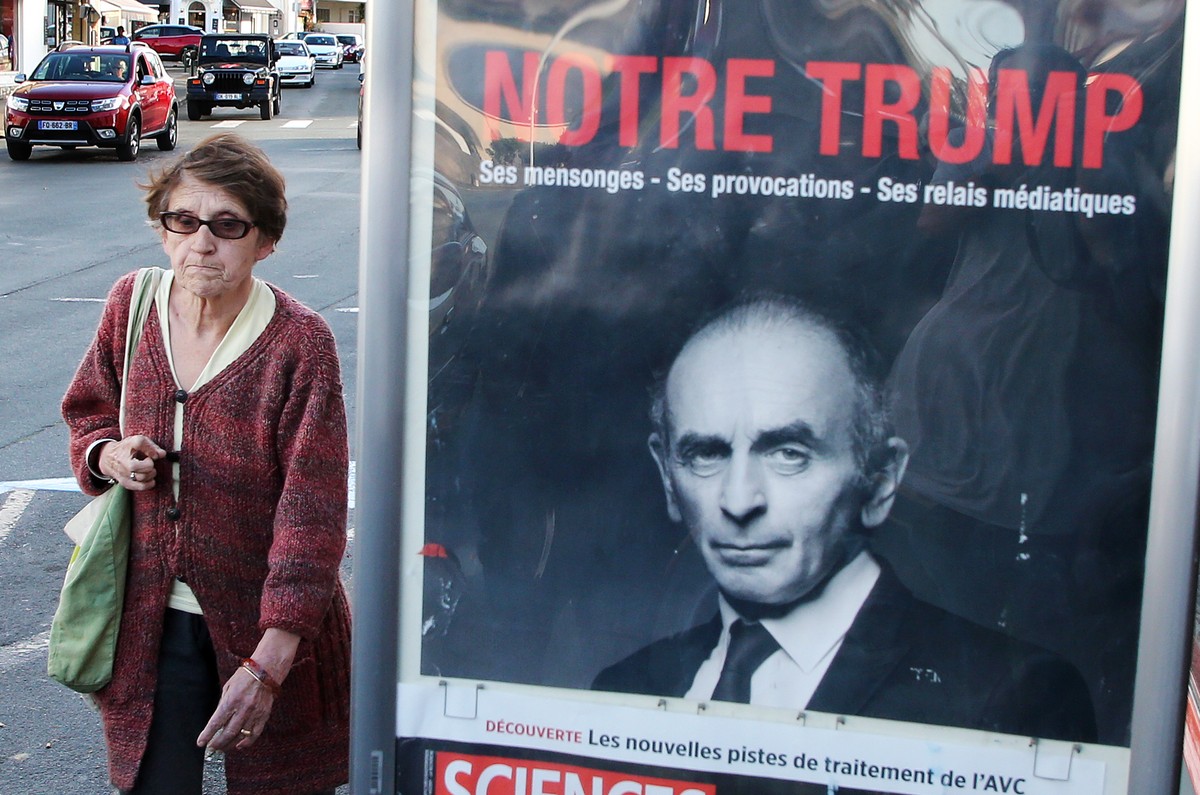 FILE - A woman walks past a poster of hard-right political talk-show star Eric Zemmour reading in French " Our Trump" in Biarritz, southwestern France, Thursday, Oct. 28, 2021. Zemmour, a fa ...
