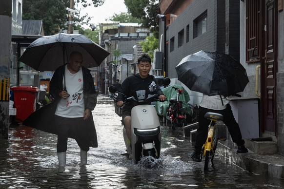 epa13093960 People use umbrellas in the aftermath of rain in the Hutong area of Beijing, China, 07 July, 2026. EPA/JESSICA LEE