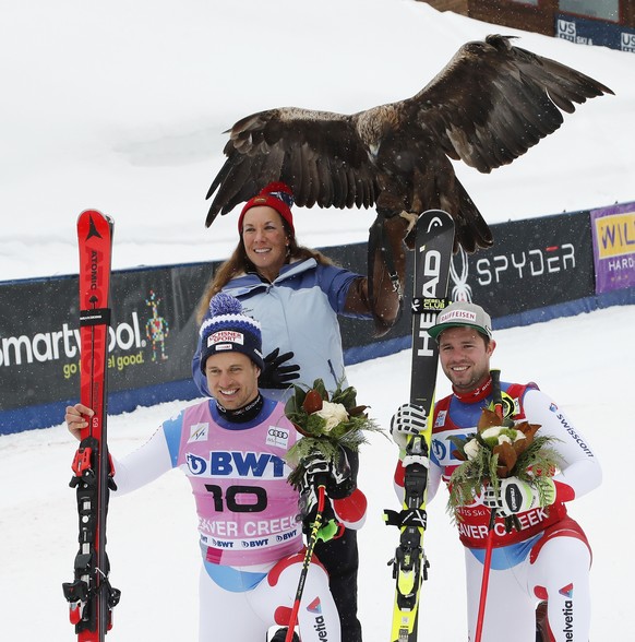 epa07200436 Winner Beat Feuz of Switzerland (R) and second placed Mauro Caviezel of Switzerland (L) pose with a Golden Eagle and handler (C) during the Men&#039;s Downhill race at the FIS Alpine Skiin ...