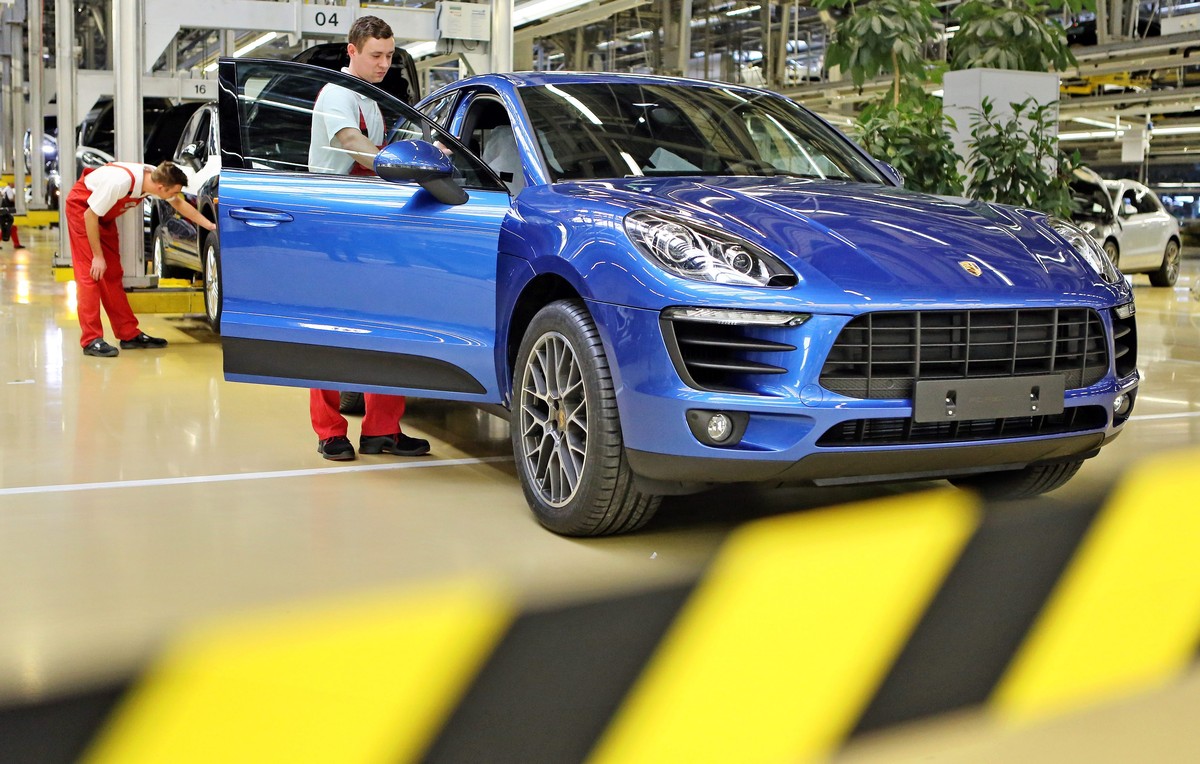 epa04069539 A photo dated 05 February 2014 and made available on 11 February 2014 shows a worker doing a final check of a new Porsche Macan vehicle at the end of an assembly line of the company's ...