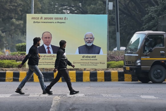 Men walk past a billboard with portraits of Indian Prime Minister Narendra Modi, right, and Russian President Vladimir Putin, hours before the scheduled arrival of the latter in New Delhi, India, Thur ...