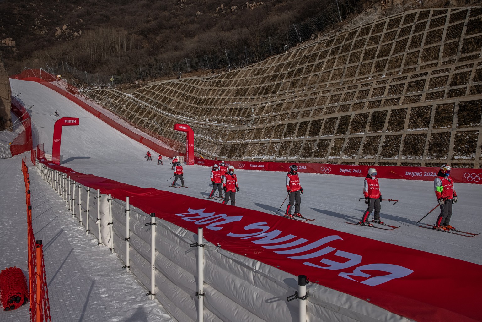 epa09718194 Side slippers crew work at Yanqing National Alpine Skiing Center, the Olympic venue for alpine skiing, in Beijing, China, 30 January 2022. The Beijing 2022 Winter Olympics is scheduled to  ...