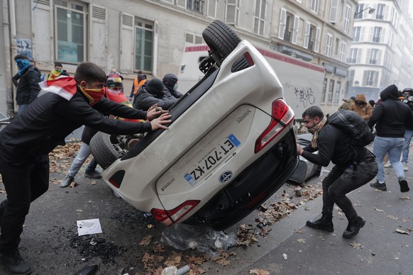 Demonstrators turn over a car during a protest against the recent shooting at the Kurdish culture center in Paris, Saturday, Dec. 24, 2022. Kurdish activists, left-wing politicians and anti-racism gro ...