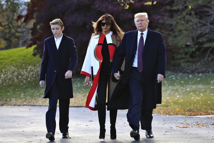 FILE- In this Tuesday, Nov. 20, 2018, file photo President Donald Trump with first lady Melania Trump and their son Barron Trump walk from the Oval Office as they leave the White House in Washington t ...