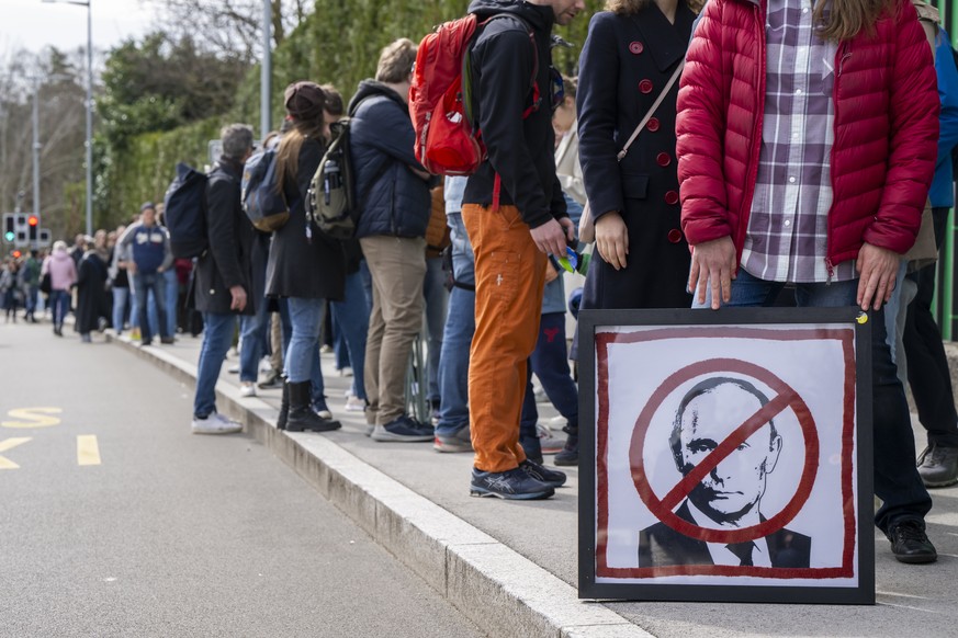 epaselect epa11225529 A protester holds a placard with a crossed-out picture of Russian President Vladimir Putin, as Russians living in Switzerland gather to protest with the slogan &#039;Noon against ...