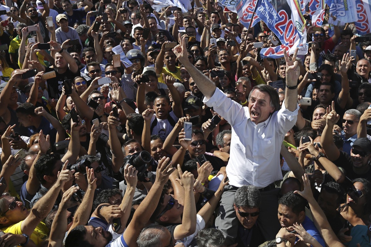 National Social Liberal Party presidential candidate Jair Bolsonaro greets supporters as he gets a shoulder ride from a member of his security detail, in Brasilia's Ceilandia neighborhood, Brazil ...