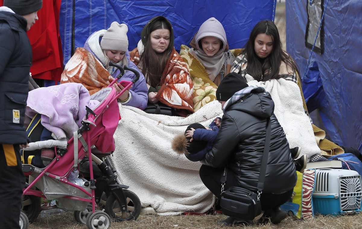 epa09789838 Ukrainian refugees, covered with blankets, recover in front of a tent after passing the Romanian-Ukrainian border crossing point in Siret, northern Romania, 27 February 2022. Romanian auth ...