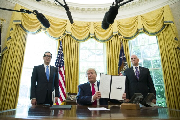 FILE - In this June 24, 2019, file photo, President Donald Trump holds up a signed executive order to increase sanctions on Iran, in the Oval Office of the White House in Washington, with Treasury Sec ...