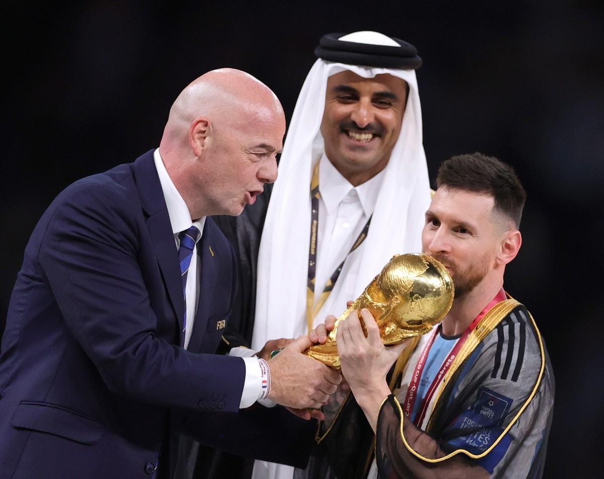 epa10373046 Lionel Messi (R) of Argentina celebrates with the World Cup trophy next to Tamim bin Hamad Al Thani (C), the Emir of Qatar, and FIFA President Gianni Infantino (L) during the trophy ceremo ...