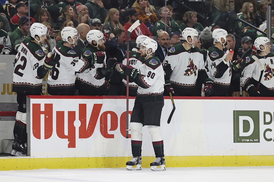 Arizona Coyotes defenseman J.J. Moser (90) is congratulated for his goal against the Minnesota Wild during the third period of an NHL hockey game Sunday, Nov. 27, 2022, in St. Paul, Minn. (AP Photo/St ...