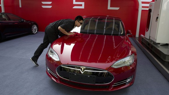 FILE - In this April 22, 2014 file photo, a worker cleans a Tesla Model S sedan before a event to deliver the first set of cars to customers in Beijing. Tesla Motors on Thursday, March 19, 2015 said i ...