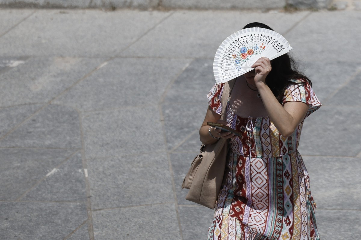 epa13058014 A woman uses a fan to protect herself from the sun in the city of Valencia, eastern Spain, 23 June 2026. The Spanish Weather Agency has issued a yellow alert due to a heat wave affecting t ...