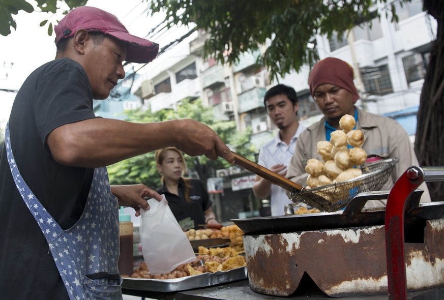 epa04912038 A Thai street vendor lifts deep fried fish balls out of a pot of oil on the side of a road in Bangkok, Thailand, 04 September 2015. Thailand&#039;s headline inflation on food prices in Aug ...