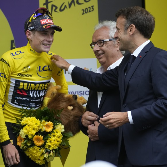 French President Emmanuel Macron congratulates overall leader Denmark&#039;s Jonas Vingegaard during th podium ceremony for the sixth stage of the Tour de France cycling race over 145 kilometers (90 m ...