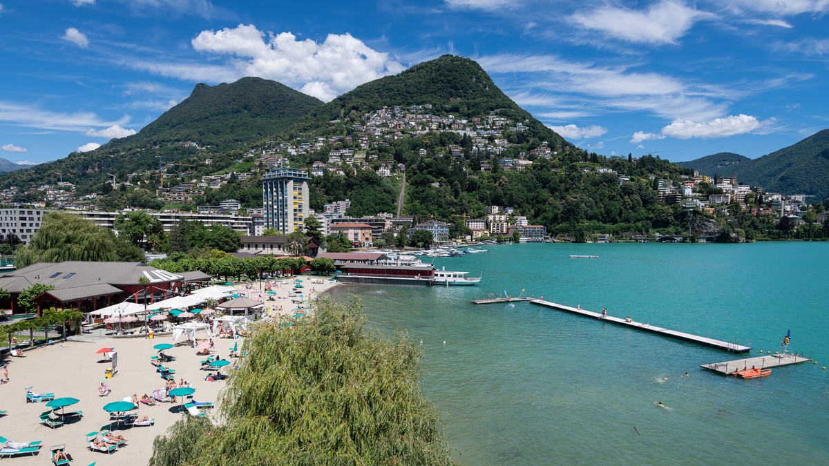epa08498377 A general view of people enjoying the sunny weather at the 'Lido di Lugano' lakeside resort and open-air swimming pool that reopened to the public in Lugano, Switzerland, 20 June ...