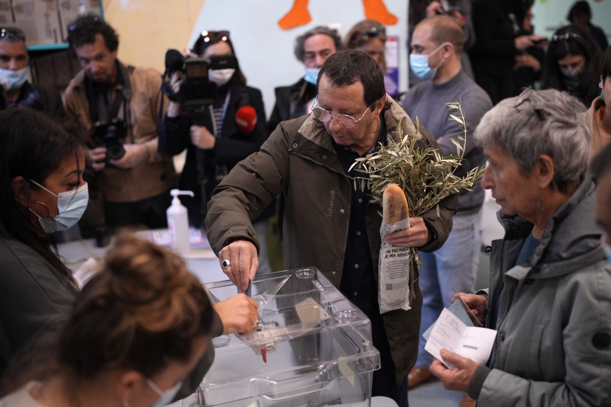 A man holding a baguette casts his ballot in the first round of the presidential election at a polling station Sunday, April 10, 2022 in Marseille, southern France. Polls opened across France for the  ...