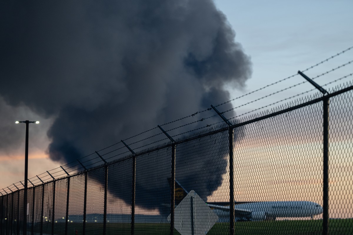 A UPS Boeing 737 is seen parked while a plume of smoke from the nearby UPS cargo plane crash is seen at Louisville Muhammad Ali International Airport on Tuesday, Nov. 4, 2025, in Louisville, Ky. (AP P ...