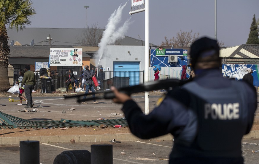 People throw stones at police as they attempt looting at Letsoho Shopping Centre in Katlehong, east of Johannesburg, South Africa, Monday, July 12, 2021. Police say six people are dead and more than 2 ...