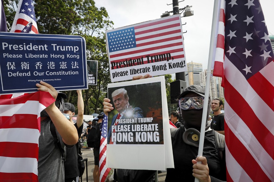 Protesters hold a placard featuring U.S. President Donald Trump and U.S. flags as they take part in a march at Victoria Park in Hong Kong, Sunday, July 21, 2019. Thousands of Hong Kong protesters marc ...