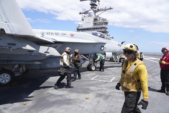 A catapult officer, right, walks past an F-16 Hornet on the flight deck of the aircraft carrier USS Gerald R. Ford during military exercises in the Mediterranean off the coast of Naples, Italy, Tuesda ...