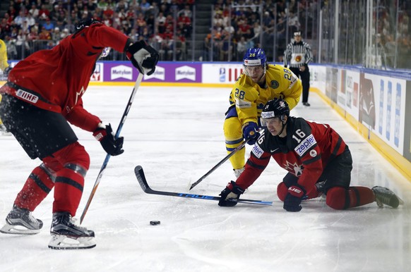 Sweden&#039;s Elias Lindholm, center, challenges for the puck with Canada&#039;s Mitch Marner during the Ice Hockey World Championships final match between Canada and Sweden in the LANXESS arena in Co ...