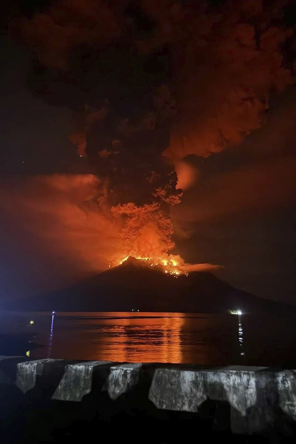 In this photo released by Sitaro Regional Disaster Management Agency (BPBD Sitaro), hot molten lava glows at the crater of Mount Ruang as it erupts in Sanguine Islands, Indonesia, Wednesday, April 17, ...