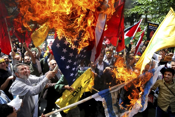 Demonstrators burn Israeli and U.S. flags to show their anger over the deaths of nearly 60 Palestinians along the Gaza border on Monday, during a protest inside the former U.S. embassy in Tehran, Iran ...