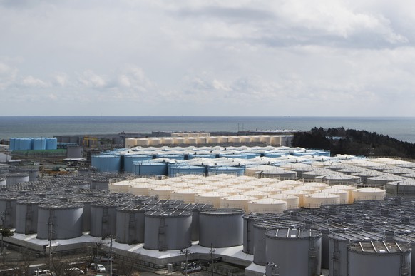 FILE - This photo shows tanks (in gray, beige and blue) storeing water that was treated but is still radioactive after it was used to cool down spent fuel at the Fukushima Daiichi nuclear power plant  ...