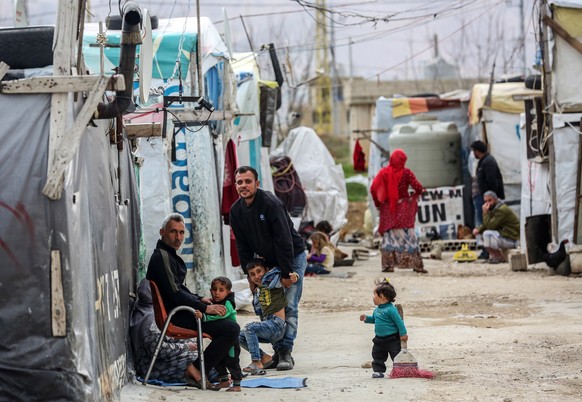 epa08290531 Syrian refugee men sit in front of makeshift tents at Al Faydah refugee camps, near Zahleh in the Bekaa Valley, Lebanon, 12 March 2020. Syrian refugees are experiencing a difficult life in ...