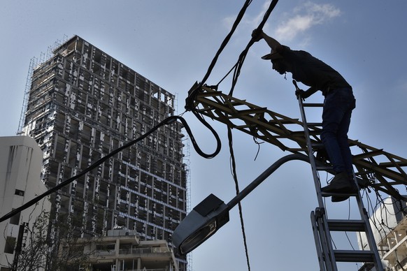 A electricity worker fixes power cables in front of a damaged building, near the scene of Tuesday&#039;s explosion that hit the seaport of Beirut, Lebanon, Friday, Aug. 7, 2020. Rescue teams were stil ...