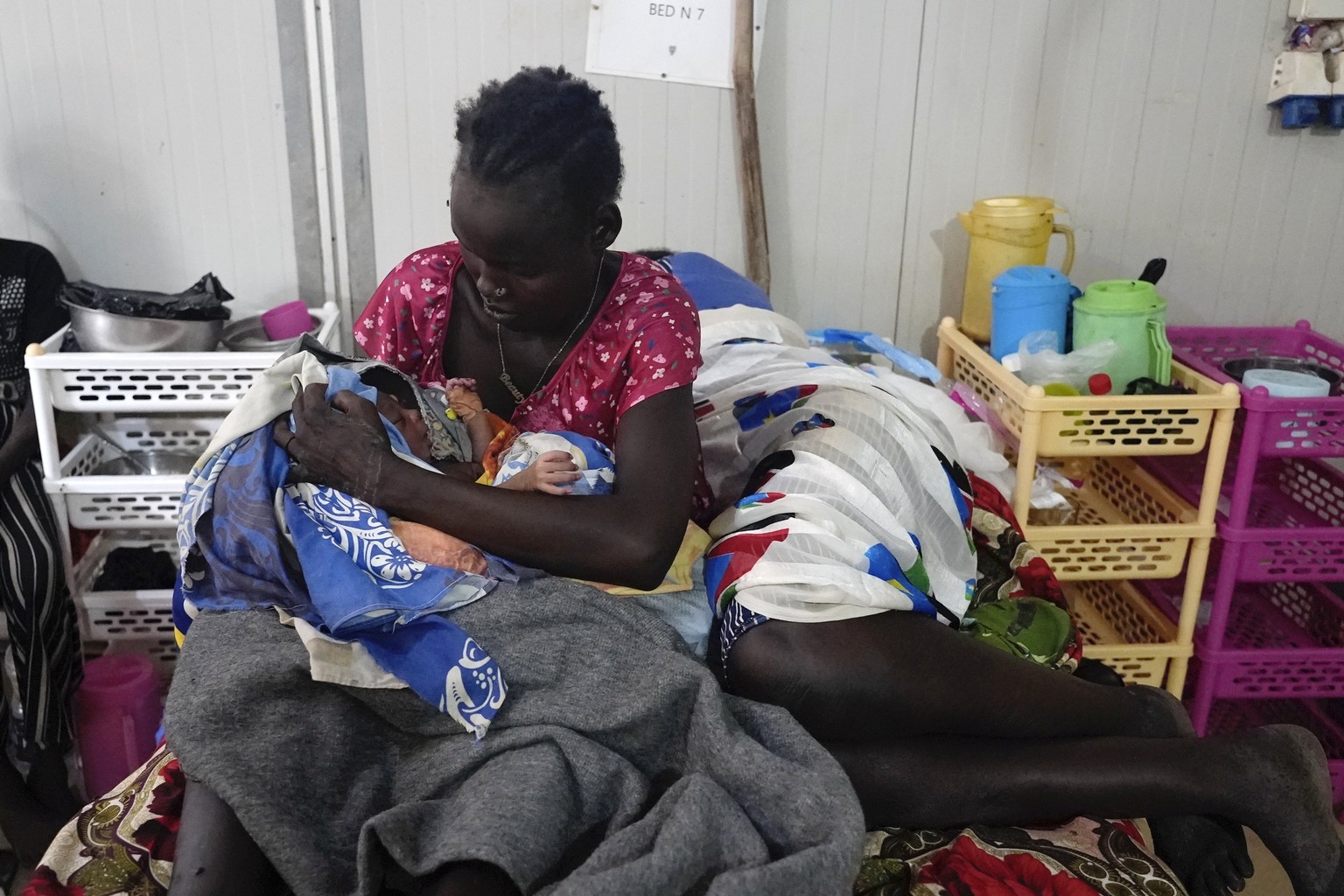 Nyalith Mauit, cradles her one-day old son on a bed in the Doctors Without Borders in Bentiu-run hospital in Bantiu, South Sudan, Monday, June 24,2024, after she lost one of her twins while giving bir ...