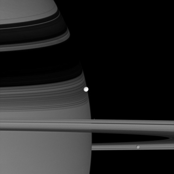 Die Saturnmonde Enceladus (hell in der Mitte), Pandora (winzig am oberen Rand der Ringe) und Mimas (unten rechts) auf einem Foto der <a href="https://de.wikipedia.org/wiki/Cassini-Huygens" target="_blank">Cassini-Sonde</a>.&nbsp;