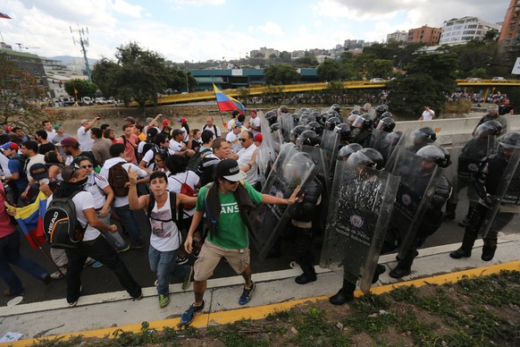 Die Polizei versucht, die jungen Demonstranten von der Blockade eines Highways in Caracas abzuhalten.