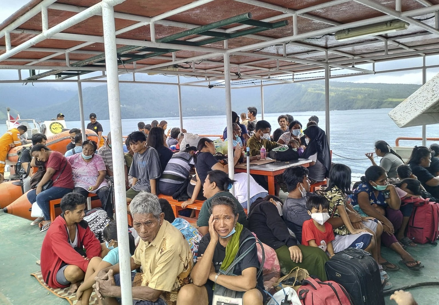 epa11311759 A handout photo made available by the Vulcanology and Geological Disaster Mitigation Center (PVMBG) of the Indonesian Ministry of Energy and Mineral Resources shows people sitting on board ...