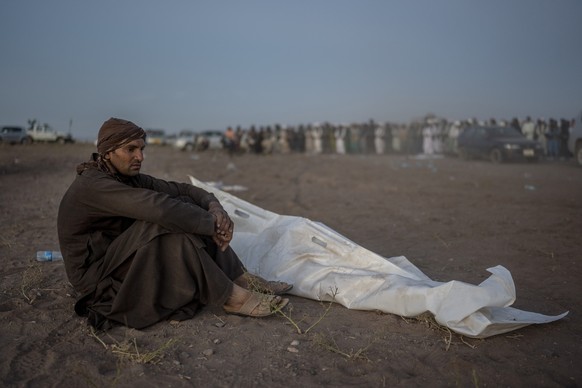 An Afghan man sits next to the body of his relative who was killed by the earthquake, at a burial site in Zenda Jan district in Herat province, western of Afghanistan, Monday, Oct. 9, 2023. Saturday&# ...