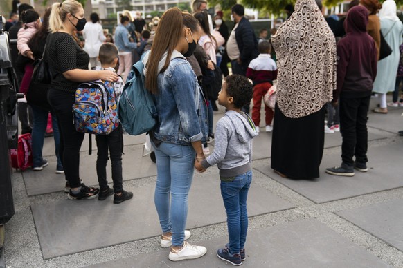 Children and relatives, wearing face masks to fight against the spread of the coronavirus, wait to enter the Heembeek primary school during the first school day of classes in Brussels, Tuesday, Sept.  ...