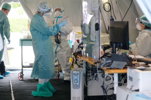 epa08292470 Health worker wearing protective suits and a face masks at work in the facility set up on the outside of Brescia&#039; Hospital to counter the Covid19 Coronavirus outbreak, Brescia, Italy, ...