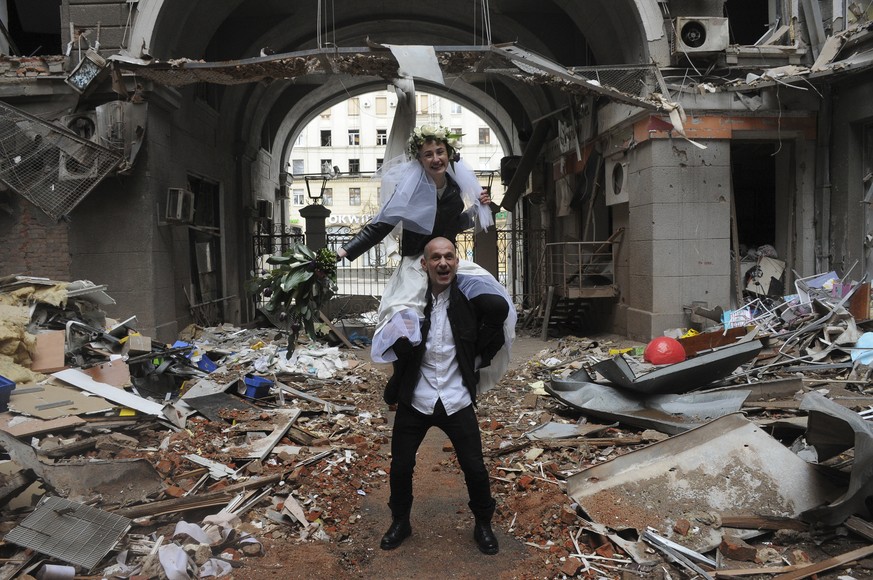 Volunteers Anastasia, top, and Anton pose for a picture in a yard of a destroyed by shelling apartment building during their wedding celebration in Kharkiv, Ukraine, Sunday, April 3, 2022. (AP Photo/A ...