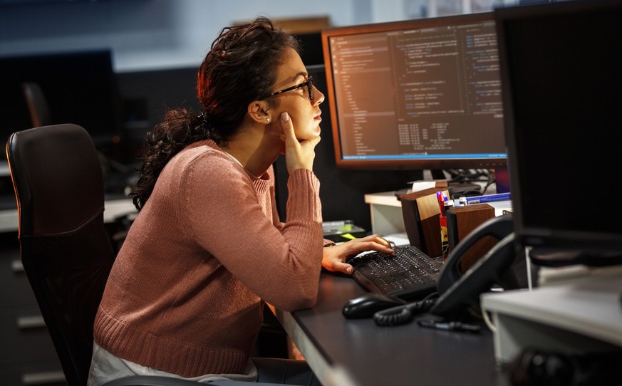 Frau vor dem PC-Bildschirm, Software-Entwicklerin (Symbolbild).