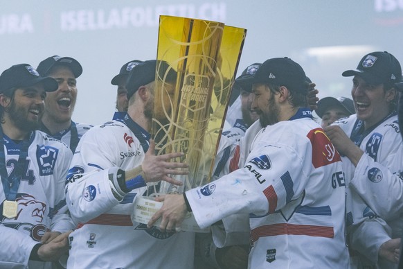 Zurich&#039;s player Patrick Geering, right, gives the trophy to teammate Mathias Seger, left, after winning the Swiss championship title, during the seventh match of the playoff final of the National ...