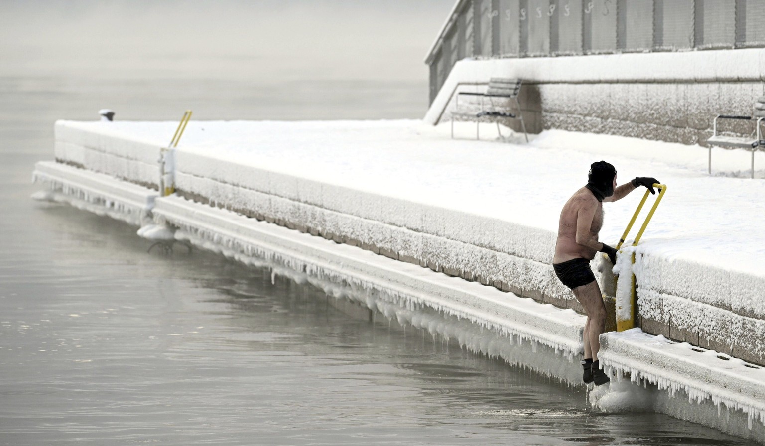 A man climbs out from the icy sea to the pier, in southern Helsinki, Finland, Tuesday, Jan. 2, 2024. Finland and Sweden have recorded this winter?s cold records on Tuesday as a temperatures plummeted  ...