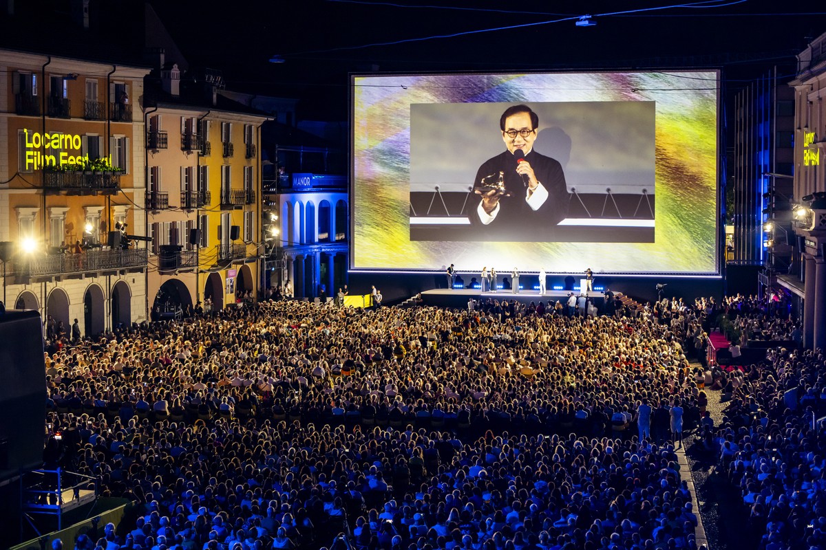 Hong Kong actor Jackie Chan reacts on a giant screen as he receives the "Pardo alla Carriera" prize at the Piazza Grande square during the 78th Locarno International Film Festival, in Locarn ...