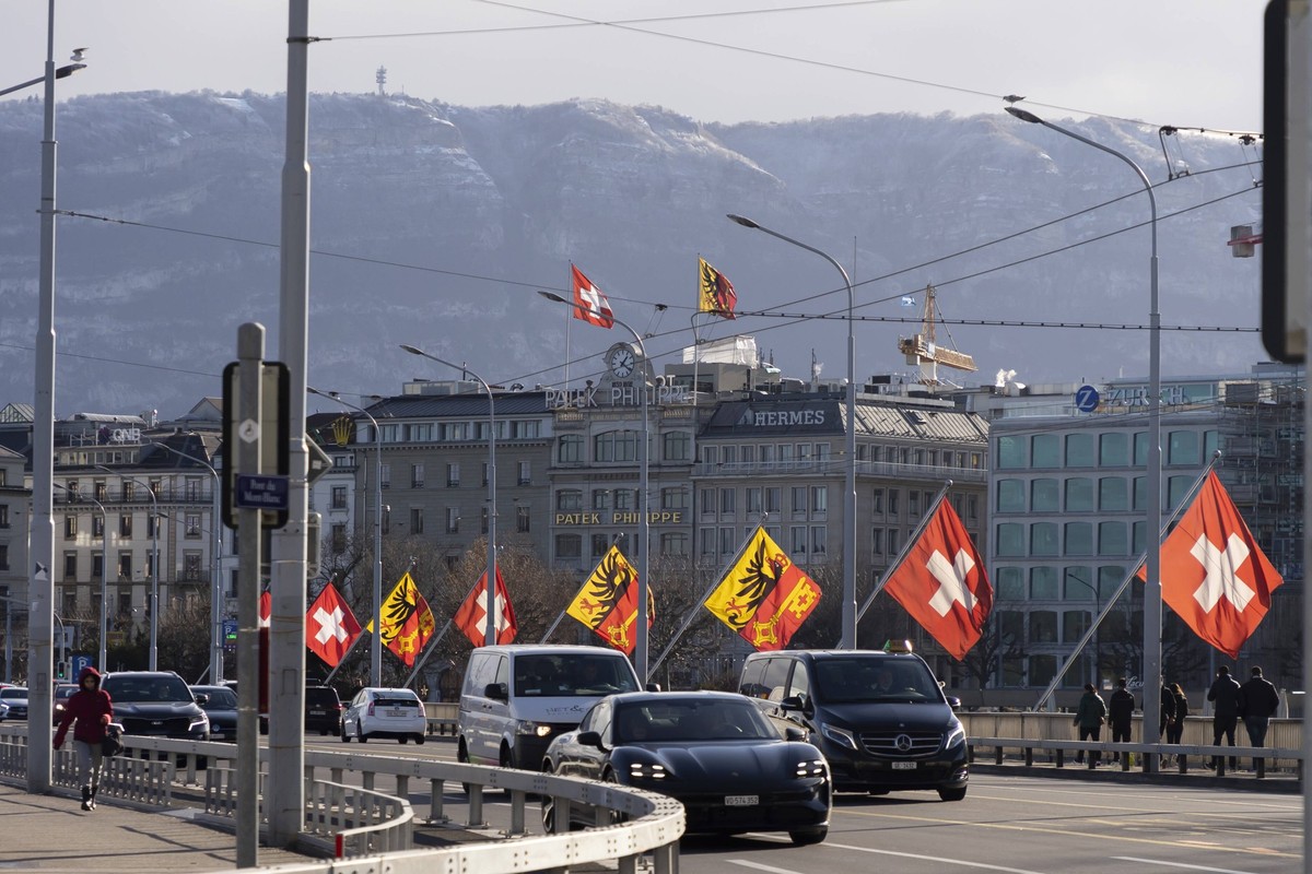 Geneva, Switzerland January 5, 2022 - Cars pass on the Mont Blanc Bridge, in the background Swiss flags The canton of Geneva hosts 39 international organizations and 431 non-governmental organizations ...