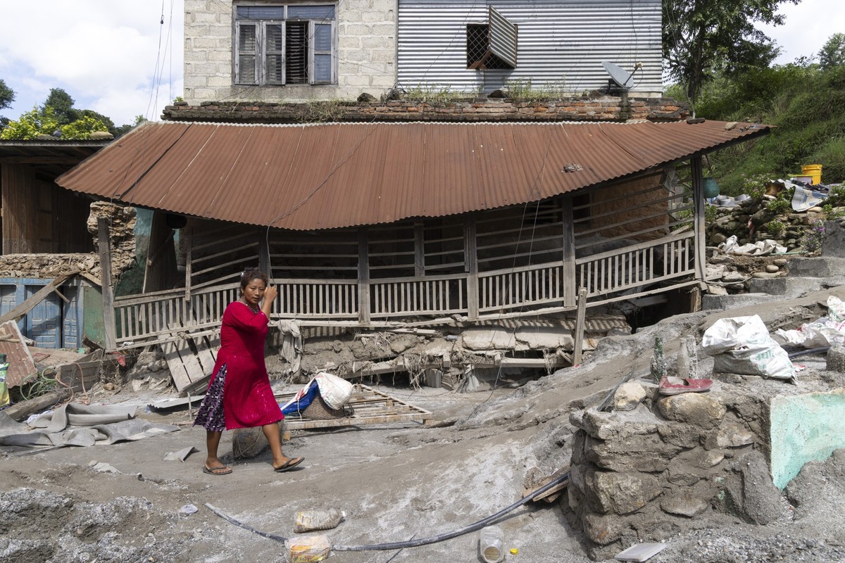 epa13200028 A woman walks in front of a damaged house following flash floods along the banks of the Trishuli River in Dhading district, Nepal, 30 August 2026. More than 700 people were killed, and hun ...