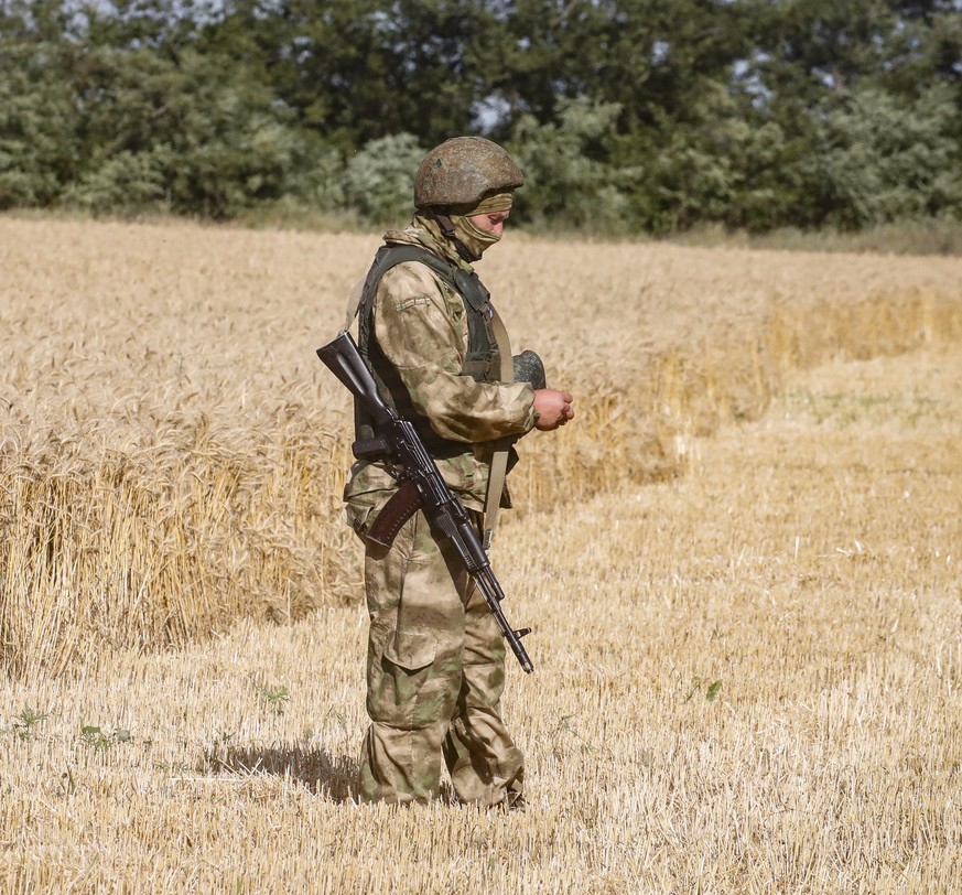 epa10072147 A picture taken during a visit to Melitopol organized by the Russian military shows a Russian serviceman standing guard in a field near Melitopol, Zaporizhia region, southeastern Ukraine,  ...