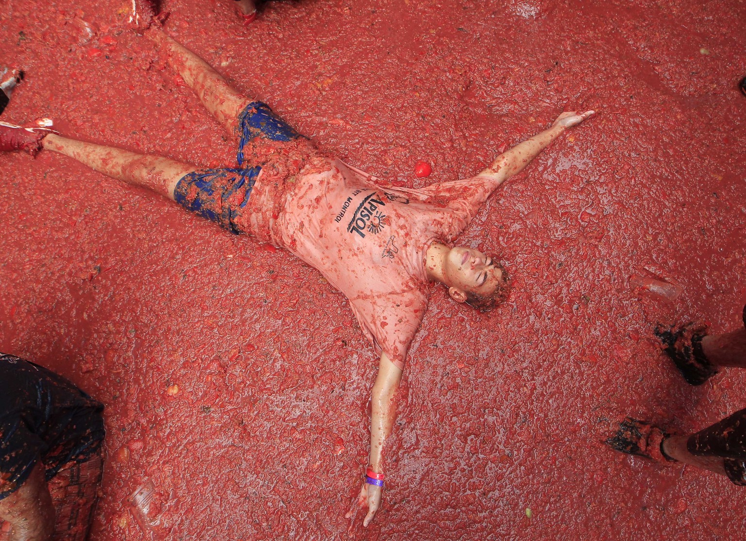 A men lies in a puddle of squashed tomatoes during the annual &quot;Tomatina&quot;, tomato fight fiesta, in the village of Bunol, 50 kilometers outside Valencia, Spain, Wednesday, Aug. 30, 2017. The s ...