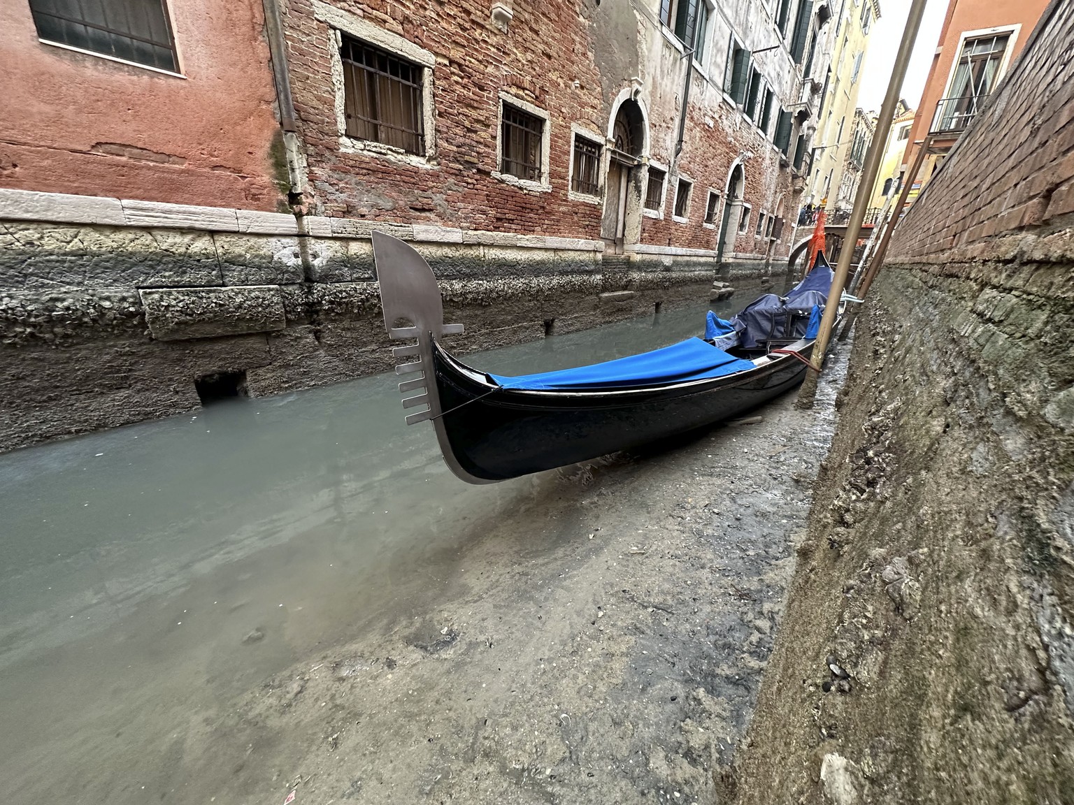A gondola is docked on a dry canal during a low tide in Venice, Italy, Monday, Feb. 20, 2023. (AP Photo/Luigi Costantini)