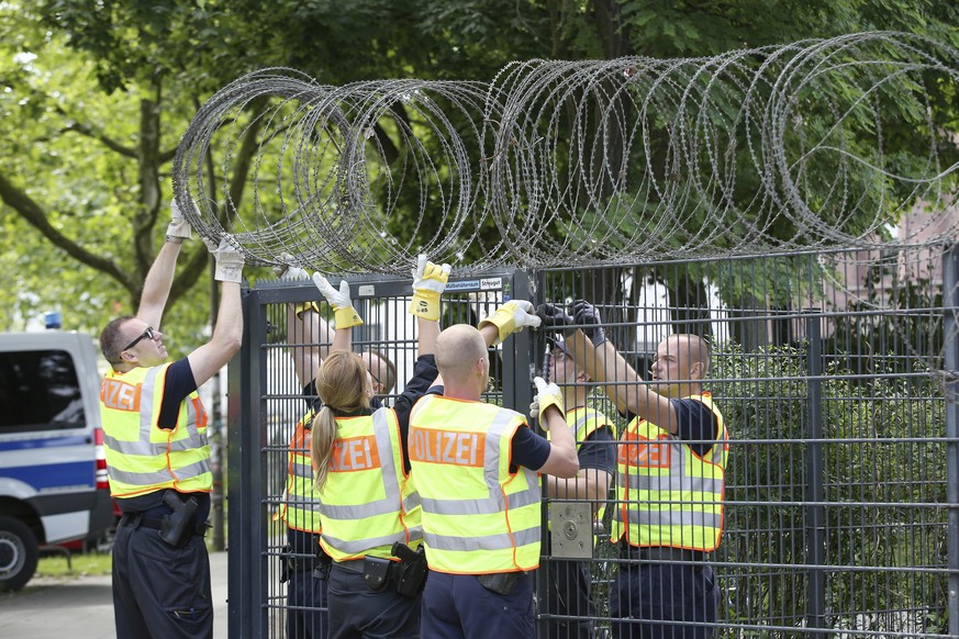 Police officers fix barbed wire on to a fence at the Sternstanze train station close to the fair grounds in Hamburg, Germany, Thursday, June 28, 2017. The G20 will take place on 7th and 8th of July. ( ...