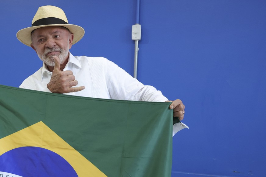 epa13280616 Brazilian presidential candidate and current President Luiz Inacio Lula da Silva holds the national flag after casting his vote at a polling station in Sao Bernardo do Campo, Brazil, 04 Oc ...