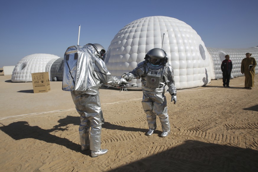 In this Feb. 7, 2018, photo, analog astronaut João Lousada, center, hands his colleague Kartik Kumar a drone while two Omani men watching in front of the Mars simulation base camp in the Dhofar desert ...